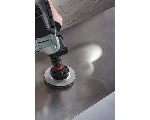 Eine Bohrmaschine mit einem Schleifaufsatz wird auf einer Metalloberfläche verwendet.