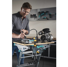 Homme portant des lunettes de protection travaillant une pièce métallique sur un établi Wolfcraft avec un outil multifonction.