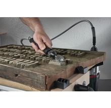 Une personne utilise un arbre flexible pour travailler une surface en bois