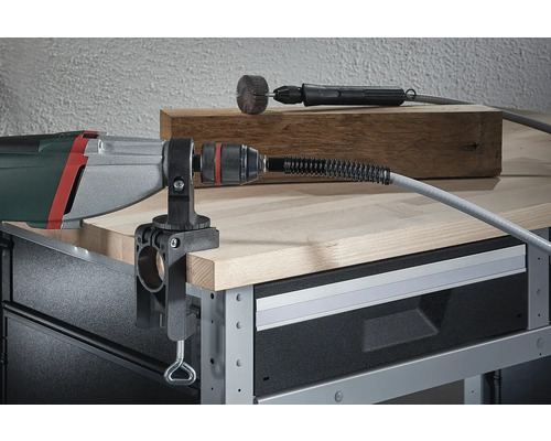 Bohrmaschine mit montierter biegsamer Welle und Tischklemme auf einer Werkbank.