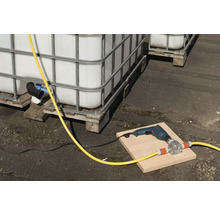 Scène avec des cuves IBC, une perceuse et une pompe à tuyau sur une planche.