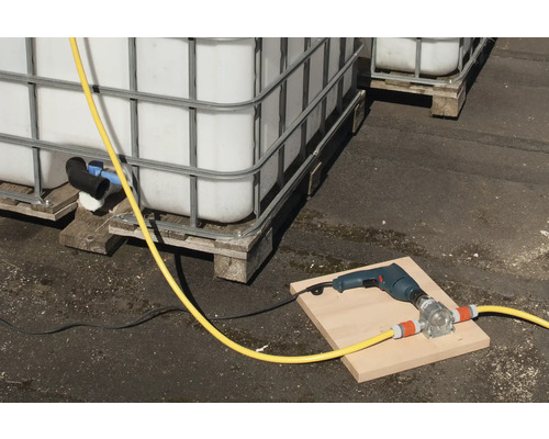 Scène avec des cuves IBC, une perceuse et une pompe à tuyau sur une planche.