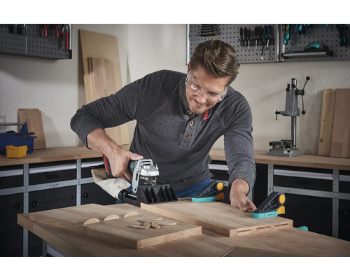 Un homme utilise une fraise à tourillons dans un atelier pour travailler des pièces en bois.