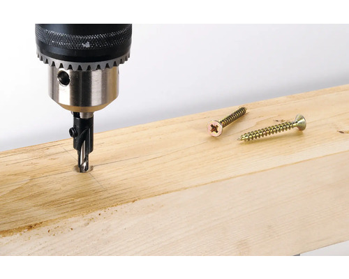 Bohrmaschine bohrt Loch in ein Holzbrett, Schrauben liegen bereit