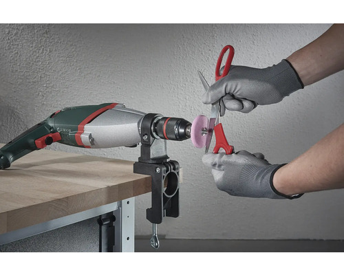 Eine Bohrmaschine mit einem montierten Schleifaufsatz wird verwendet, um eine Schere zu schärfen.