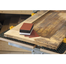 Bloc de ponçage et papier abrasif sur une table en bois.