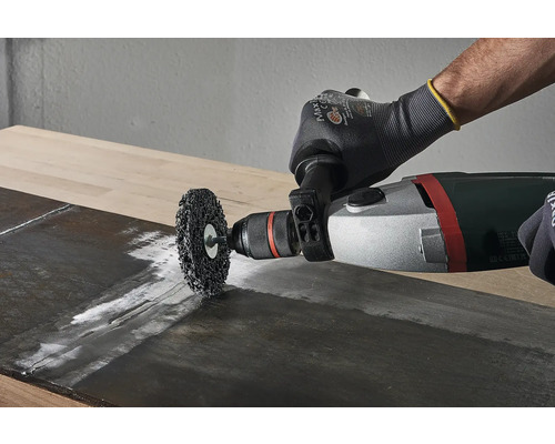 Eine Drahtbürste wird mit einer Bohrmaschine auf einem Holzbrett verwendet.