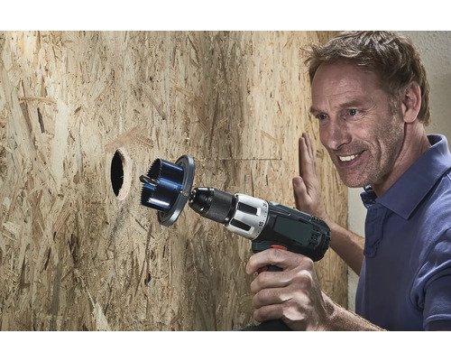 Un homme perce un trou dans une paroi en bois avec une scie-cloche.