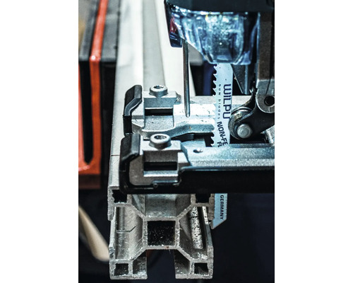 Vue détaillée d''une scie sauteuse coupant un profilé métallique.