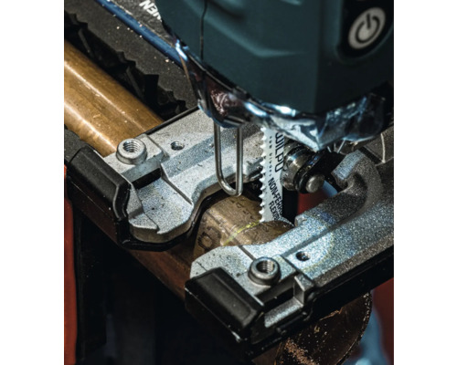 Gros plan d''une scie sauteuse coupant un tuyau métallique.