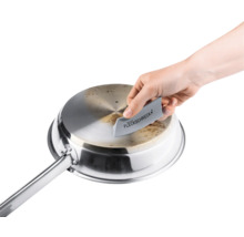 Eine Person reinigt eine Edelstahlpfanne mit einem Fleckentferner