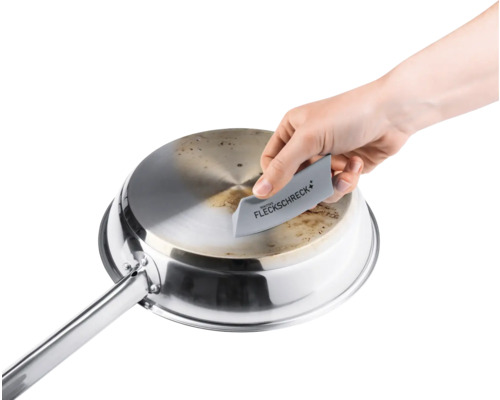 Eine Person reinigt eine Edelstahlpfanne mit einem Fleckentferner