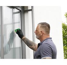 Une personne utilise un grattoir à vitre pour nettoyer une vitre.