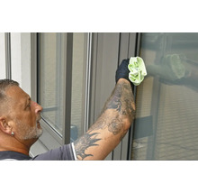 Un homme tatoué nettoie les fenêtres avec un chiffon