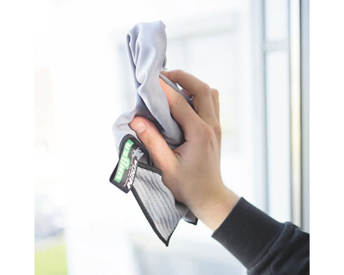 Eine Hand hält ein Unger Ninja Reinigungstuch vor einem Fenster.