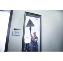Une femme nettoie une fenêtre avec une vadrouille triangulaire dans une salle de conférence.