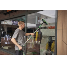 Un homme nettoie une vitrine avec un nettoyeur de vitres.