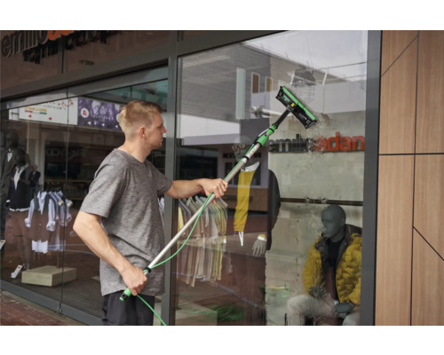 Un homme nettoie une vitrine avec un nettoyeur de vitres.