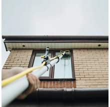Nettoyage de fenêtre avec une brosse à manche télescopique sur une maison