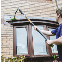 Nettoyage des fenêtres avec une brosse à manche télescopique sur une maison.