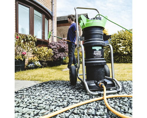 Photo extérieure d''une personne nettoyant une fenêtre avec un système de nettoyage de fenêtres Unger. Au premier plan se trouve le système de nettoyage de fenêtres Unger Hydro Power Ultra avec chariot.