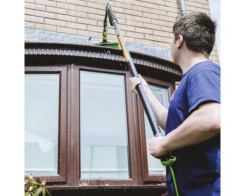 Homme nettoyant les fenêtres avec un lave-vitre télescopique