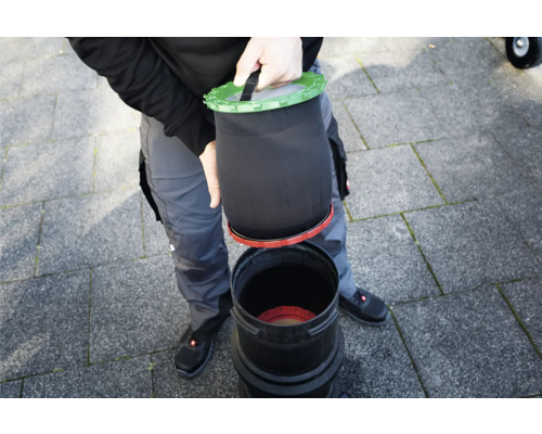 Person setzt Filtersack in eine Filtertonne
