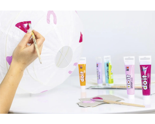 Une personne peint une lanterne en papier avec de la peinture pour loisirs créatifs.