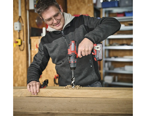 Ein Mann bohrt mit einem Akku-Bohrschrauber ein Loch in ein Holzbrett.