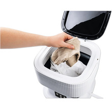 Le linge est placé dans une machine à laver portable.