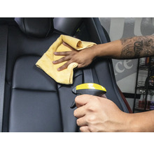 Reinigung eines Autositzes mit Reinigungsmittel und Tuch.