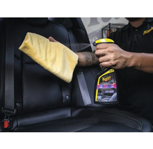 Person reinigt Autositz mit Lederreiniger und Tuch