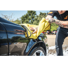 Person trocknet ein Auto mit einem Mikrofasertuch