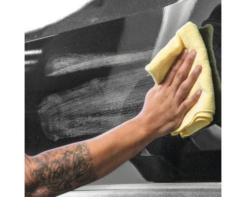 Reinigung eines schwarzen Autos mit einem Tuch.