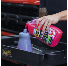 Eine Person gießt Autoshampoo in einen Behälter für Autowäsche. Meguiar''s Logo