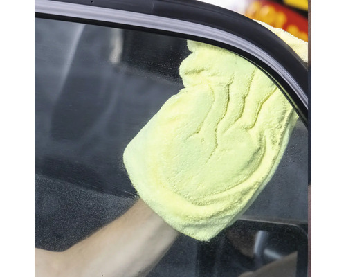 Eine Person reinigt eine Autoscheibe mit einem gelben Tuch.