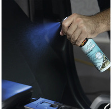 Eine Hand sprüht Lufterfrischer in das Innere eines Autos.