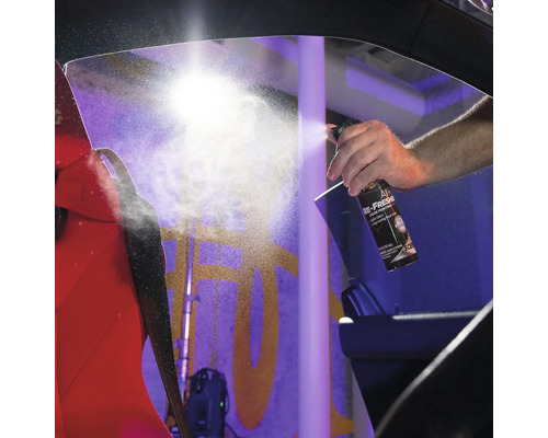 Ein Mann sprüht Lufterfrischer in ein Auto, um Gerüche zu bekämpfen.