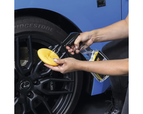 Autopflege: Person reinigt Felge mit Schwamm und Reiniger