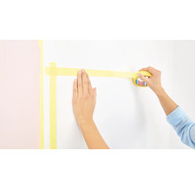 Person klebt Malerkrepp an eine Wand