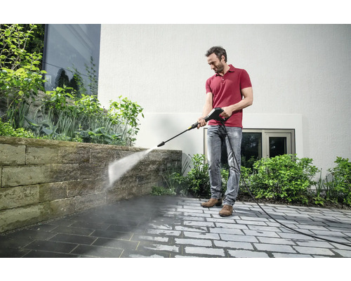 Un homme nettoie la terrasse avec un nettoyeur haute pression.
