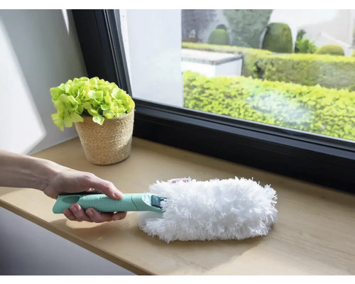 Person hält Staubwedel mit Griff zum Reinigen auf Fensterbank