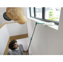 Femme nettoie le cadre de la fenêtre avec un plumeau.
