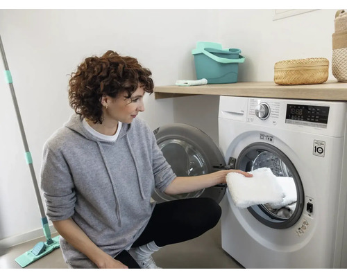 Frau legt einen waschbaren Wischbezug in eine Waschmaschine.