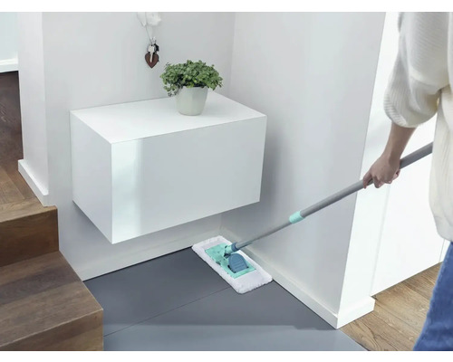 Reinigungskraft wischt Boden im Eingangsbereich mit einem Mopp