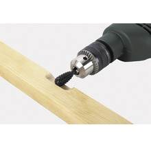 Eine Bohrmaschine mit einem Raspelaufsatz bearbeitet ein Holzstück.