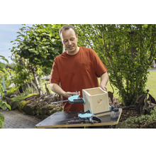 Un homme construit un nichoir avec des serre-joints sur un établi dans le jardin.