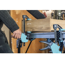 Artisan fixant du bois avec une serre-joint à une main sur un établi