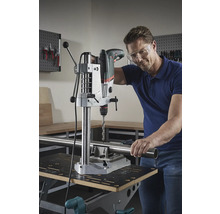 Mann bohrt mit einer Tischbohrmaschine ein Rohr auf einer Werkbank