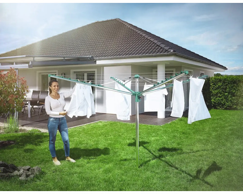 Drehflügelwäscheständer im Garten mit aufgehängter Wäsche und Frau